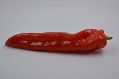 Sağlık, sağlıklı yiyecekler, sebzeler, sağlıklı yiyecekler. Yeşil kuyruklu uzun kırmızı bir dolma biber beyaz bir arka planda yer alır..