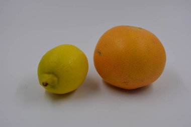 Sağlık, sağlıklı yiyecekler, meyveler, uygun beslenme. Bir sarı limon ve bir kırmızı-turuncu greyfurt beyaz arka plana yerleştirilmiş..