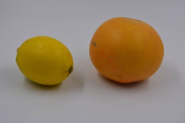 Sağlık, sağlıklı yiyecekler, meyveler, uygun beslenme. Bir sarı limon ve bir kırmızı-turuncu greyfurt beyaz arka plana yerleştirilmiş..