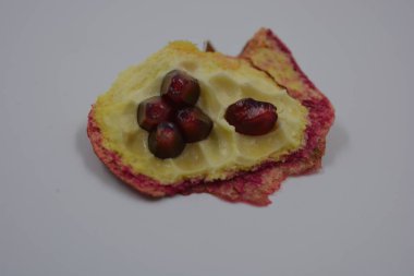 Sağlık, sağlıklı yiyecekler, meyveler, uygun beslenme. Beyaz, açık tenli, kırmızı-turuncu greyfurt ve beyaz arka planda kırmızı-kiraz sulu tohumlar..