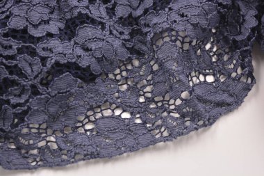 Alışılmadık kumaşlar, buruşuk koyu mavi pamuk, çiçekli güzel dantelli viskoz beyaz plastik arka planda yer alır..