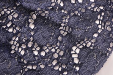 Alışılmadık kumaşlar, buruşuk koyu mavi pamuk, çiçekli güzel dantelli viskoz beyaz plastik arka planda yer alır..