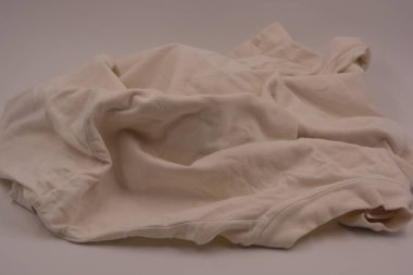 Alışılmadık, eski, yoğun yaz kumaşı. Pamuk, iyi dövülmüş kumaş, kadın kıyafeti, buruşuk tişört beyaz plastik arka planda yer alıyor..