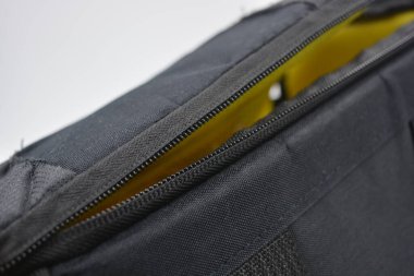 Çantalar, fermuarlı ürünler günlük yaşam için. Sarı astarlı, siyah fermuarlı ve cepli kırılgan ekipmanları saklamak ve taşımak için küçük siyah bir çanta beyaz arka planda yer almaktadır..