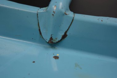 Yaşlı, bastırılmış ve yıpranmış. Boyanın çıktığı mavi Fin metal kepçesi siyah bir arka planda bulunur..