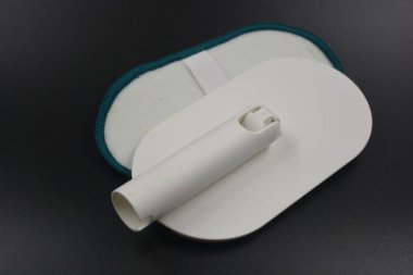 Yeşil mikrofiberli plastik beyaz alet, bez. Pencereleri yıkamak ve temizlemek için bir nesne, siyah, mat plastik arka planda yer alan bir cam..