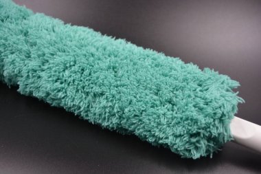 Güzel yeşil yumuşacık, naylon, beyaz plastik tabanlı sentetik kumaş, odayı tozdan temizlemek ve temizlemek için sapı siyah plastik bir arka planda yer almaktadır..