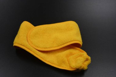 Alışılmadık bir temizlik bezi, uzun sarı bir mikro fiber seti siyah, mat plastik arka plan.