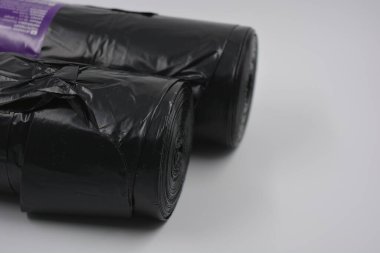 İki paket plastik siyah çanta, yuvarlak büyük rulo beyaz plastik arka plan üzerine dizilmiş..