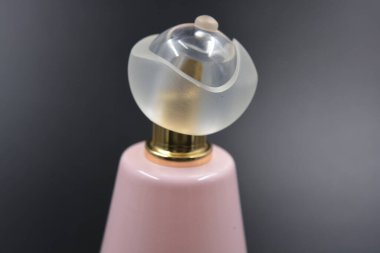 Kadın eşyaları, parfümler, hoş kokular. Hoş bir çilek parfümlü zarif bir pembe şişe, bir mat beyaz plastik şapka ve bir altın püskürtücü siyah plastik arka planda düzenlenir..