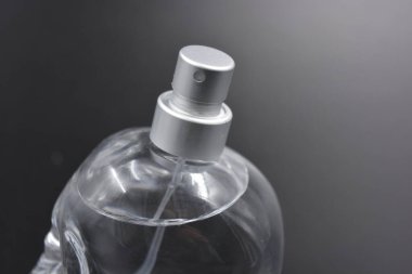 Kadın eşyaları, parfümler, hoş kokular. Kafatası şekilli parfümlü zarif cam şişe, siyah plastik arka planda gümüş sprey düzenleyici..