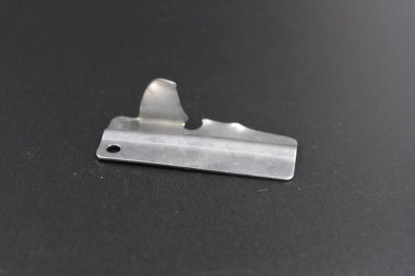 Alışılmadık metal şeyler, konserve yiyecekler için metal bir parça siyah plastik arka planda bulunur..