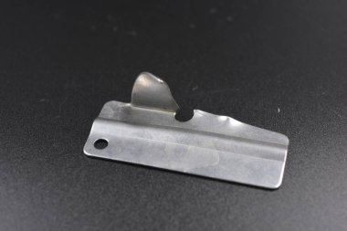 Alışılmadık metal şeyler, konserve yiyecekler için metal bir parça siyah plastik arka planda bulunur..
