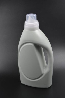 Çamaşır, çarşaf ve kumaşlar için büyük gri bir şişe. Siyah plastik arka planda, şeffaf kapaklı mor, yapışkan bir sıvıyla dolu plastik bir şişe bulunur..