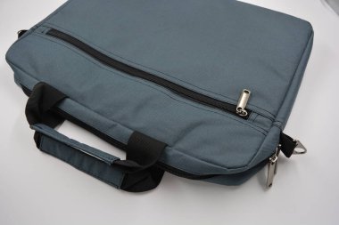 Günlük eşyalar, ekipmanlar, yeşil, gri, siyah metal fermuarlı yumuşak laptop çantası siyah plastik bir arka planda yer almaktadır..