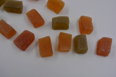 Food, delicious sweet jelly candies sprinkled with sugar are arranged on a white plastic background. Green, red, yellow, orange small bars of marmalade.  clipart