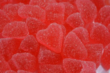 Yiyecek, şeker serpiştirilmiş tatlı jöle şekerler beyaz plastik arka planda düzenlenir. Kalp şeklinde kırmızı, pembe marmelat, çok sayıda kalbin arka planı.. 