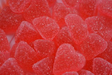 Yiyecek, şeker serpiştirilmiş tatlı jöle şekerler beyaz plastik arka planda düzenlenir. Kalp şeklinde kırmızı, pembe marmelat, çok sayıda kalbin arka planı.. 