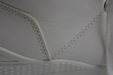 Kumaş arka plan, beyaz deri kumaştan malzemeler, plastik, kauçuk. Beyaz yüzey beyaz ipliklerle dikilmiş, malzeme yıpranmış..