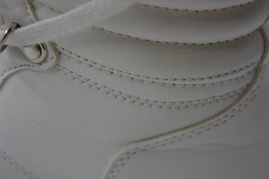 Kumaş arka plan, beyaz deri kumaştan malzemeler, plastik, kauçuk. Beyaz yüzey beyaz ipliklerle dikilmiş, malzeme yıpranmış..