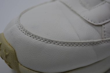 Yıkanmış, yıpranmış kadın ayakkabıları. Lekeli ve çatallı eski püskü ayakkabılar. Güzel beyaz klasik kadın botları metal perçinler ve beyaz bağcıklar beyaz plastik arka planda..