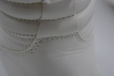 Kumaş arka plan, beyaz deri kumaştan malzemeler, plastik, kauçuk. Beyaz yüzey beyaz ipliklerle dikilmiş, malzeme yıpranmış..