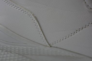 Kumaş arka plan, beyaz deri kumaştan malzemeler, plastik, kauçuk. Beyaz yüzey beyaz ipliklerle dikilmiş, malzeme yıpranmış..