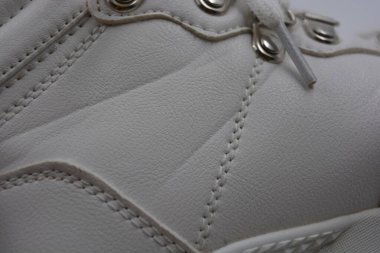 Yıkanmış, yıpranmış kadın ayakkabıları. Lekeli ve çatallı eski püskü ayakkabılar. Güzel beyaz klasik kadın botları metal perçinler ve beyaz bağcıklar beyaz plastik arka planda..