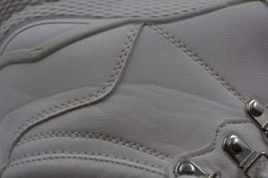 Yıkanmış, yıpranmış kadın ayakkabıları. Lekeli ve çatallı eski püskü ayakkabılar. Güzel beyaz klasik kadın botları metal perçinler ve beyaz bağcıklar beyaz plastik arka planda..