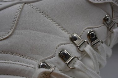 Yıkanmış, yıpranmış kadın ayakkabıları. Lekeli ve çatallı eski püskü ayakkabılar. Güzel beyaz klasik kadın botları metal perçinler ve beyaz bağcıklar beyaz plastik arka planda..