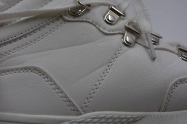 Yıkanmış, yıpranmış kadın ayakkabıları. Lekeli ve çatallı eski püskü ayakkabılar. Güzel beyaz klasik kadın botları metal perçinler ve beyaz bağcıklar beyaz plastik arka planda..