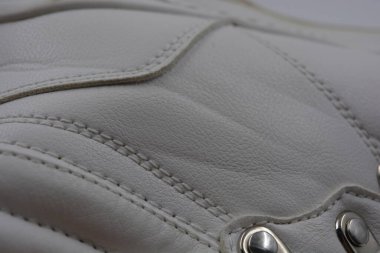 Kumaş arka plan, beyaz deri kumaştan malzemeler, plastik, kauçuk. Beyaz yüzey beyaz ipliklerle dikilmiş, malzeme yıpranmış..