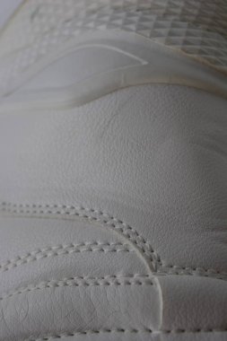 Kumaş arka plan, beyaz deri kumaştan malzemeler, plastik, kauçuk. Beyaz yüzey beyaz ipliklerle dikilmiş, malzeme yıpranmış..