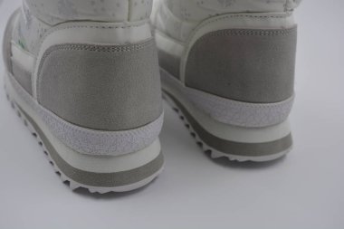 Eşyalar, gümüş kar taneleri ve gri deri ceketli kış kadın botları. Güzel beyaz kumaş yumuşak kama botlar beyaz plastik bir arka planda kurulur..