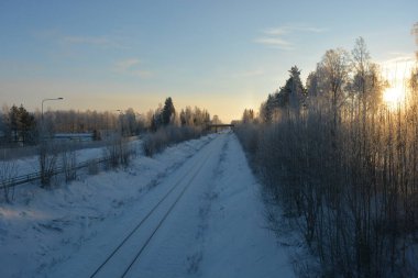 Mimarlık, inşaat, kış güzelliği. Beyaz kar, doğa ve çiğnenmiş karlı yolların arka planında demiryolu üzerinde küçük tahta bir köprü..
