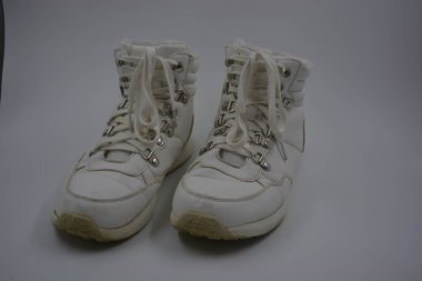 Eşyalar, ev eşyaları, ilginç tabanlı beyaz ayakkabılar, beyaz bağcıklar. Yıkanmamış, eski, yıpranmış metal perçinli kadın ayakkabıları ve aşınmış deri bir yüzey beyaz plastik bir yüzey üzerindedir..