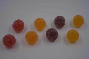 Beyaz şekerle kaplı yuvarlak toplar şeklinde orijinal Finlandiya şekerleri. Sarı, turuncu, kiraz, kırmızı jelibon şekerleri beyaz plastik arka planda bulunur..