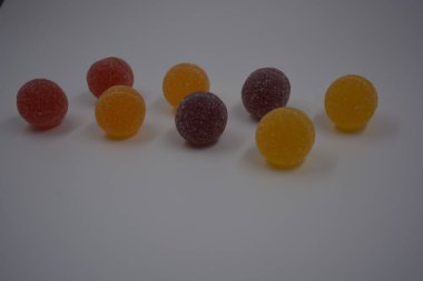 Beyaz şekerle kaplı yuvarlak toplar şeklinde orijinal Finlandiya şekerleri. Sarı, turuncu, kiraz, kırmızı jelibon şekerleri beyaz plastik arka planda bulunur..