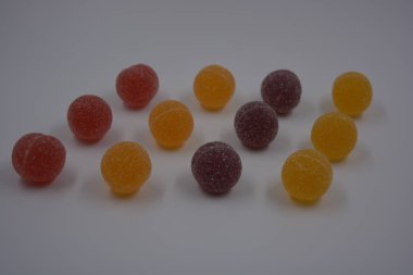 Beyaz şekerle kaplı yuvarlak toplar şeklinde orijinal Finlandiya şekerleri. Sarı, turuncu, kiraz, kırmızı jelibon şekerleri beyaz plastik arka planda bulunur..