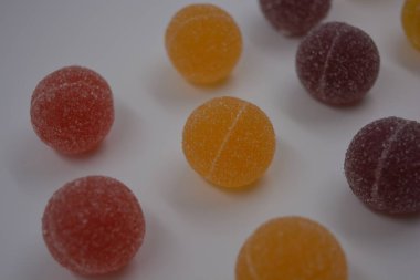 Beyaz şekerle kaplı yuvarlak toplar şeklinde orijinal Finlandiya şekerleri. Sarı, turuncu, kiraz, kırmızı jelibon şekerleri beyaz plastik arka planda bulunur..