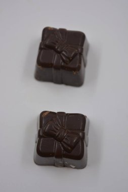 Güzel, alışılmadık ve lezzetli tatlılar, çikolatalar. Beyaz plastik arka planda siyah, süt ve beyaz çikolatadan yapılmış Belçika tatlısı bulunur..