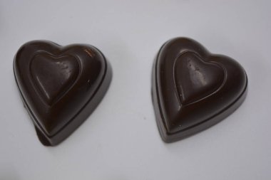 Güzel, alışılmadık ve lezzetli tatlılar, çikolatalar. Beyaz plastik arka planda siyah, süt ve beyaz çikolatadan yapılmış Belçika tatlısı bulunur..