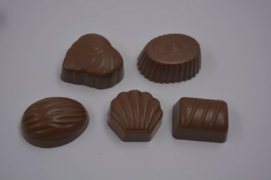 Yiyecek, yiyecek, çok lezzetli süt şekerlemeleri beyaz plastiğin üzerinde bulunur. Çikolatalar yapraklar, cevizler, madalyonlar şeklinde yuvarlak ve kare şeklinde yapılır..