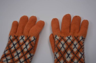 Sıcak, yumuşak, kışlık eşyalar ve ev eşyaları. Güzel turuncu, gri, yalıtılmış, örgü eldivenler beyaz plastik bir arka planda bulunur..