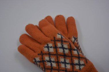 Sıcak, yumuşak, kışlık eşyalar ve ev eşyaları. Güzel turuncu, gri, yalıtılmış, örgü eldivenler beyaz plastik bir arka planda bulunur..