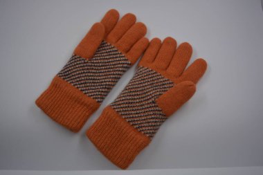Sıcak, yumuşak, kışlık eşyalar ve ev eşyaları. Güzel turuncu, gri, yalıtılmış, örgü eldivenler beyaz plastik bir arka planda bulunur..