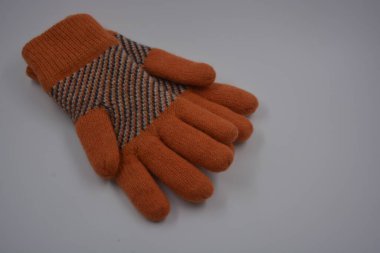 Sıcak, yumuşak, kışlık eşyalar ve ev eşyaları. Güzel turuncu, gri, yalıtılmış, örgü eldivenler beyaz plastik bir arka planda bulunur..