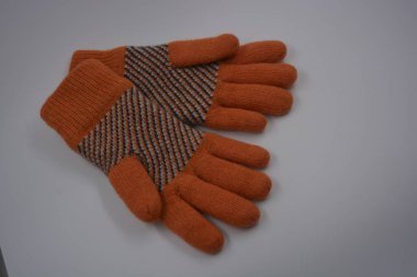 Sıcak, yumuşak, kışlık eşyalar ve ev eşyaları. Güzel turuncu, gri, yalıtılmış, örgü eldivenler beyaz plastik bir arka planda bulunur..