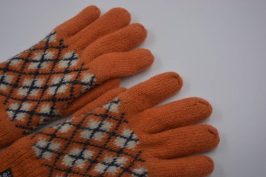 Sıcak, yumuşak, kışlık eşyalar ve ev eşyaları. Güzel turuncu, gri, yalıtılmış, örgü eldivenler beyaz plastik bir arka planda bulunur..