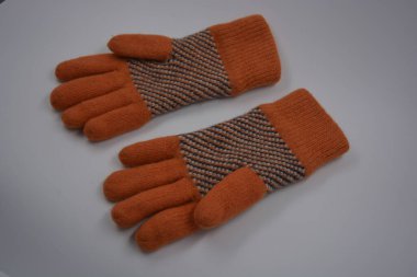 Sıcak, yumuşak, kışlık eşyalar ve ev eşyaları. Güzel turuncu, gri, yalıtılmış, örgü eldivenler beyaz plastik bir arka planda bulunur..